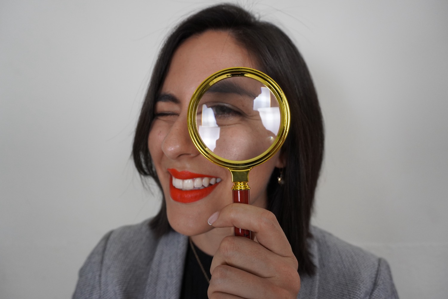 Majo Mieles V. sonriendo y mirando a través de una lupa